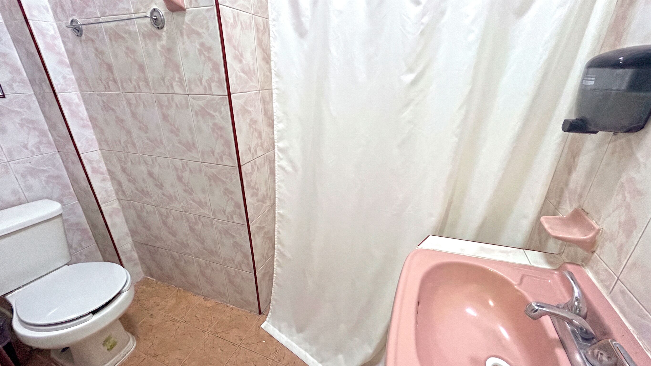 Un baño con inodoro, ducha con cortina y lavamanos.