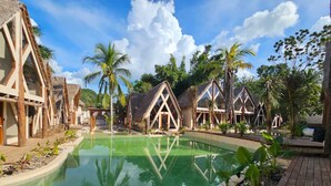 A resort with thatched-roof cottages, a central pool, and tropical vegetation. - KAAJ NDOMI (Bacalar)