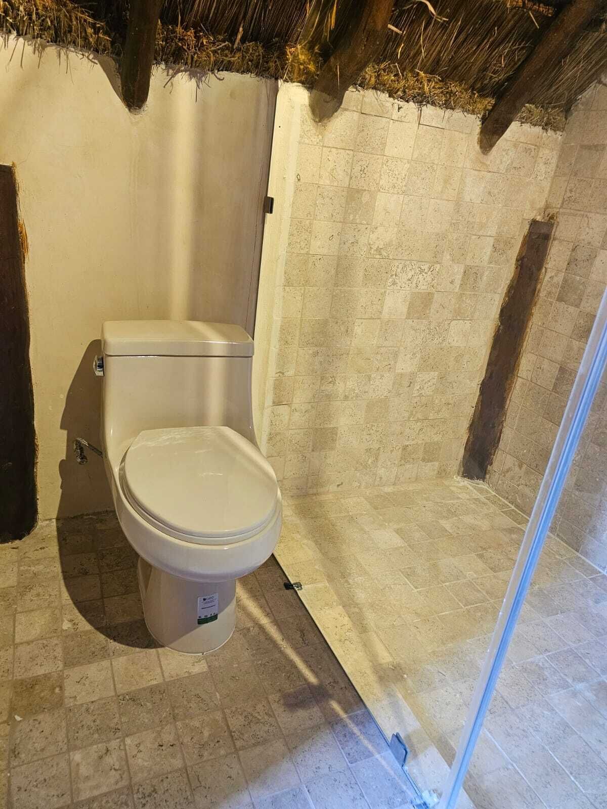 Une salle de bain comprenant des toilettes, un espace douche et un sol carrelé.