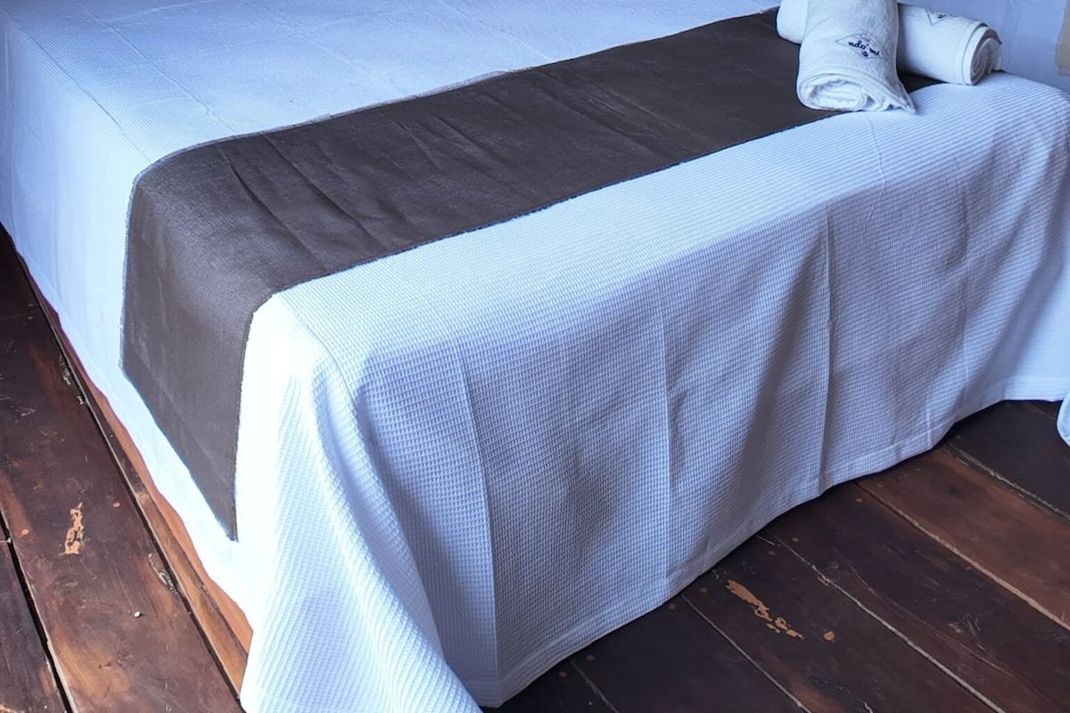 Una habitación con dos camas, cabeceros de madera y techo de paja.