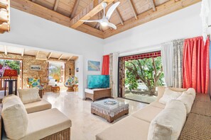 A spacious living area with a high ceiling, a television, and a large window with curtains. - 4-bedroom Villa in beautiful Savaneta with cool AC (Savaneta)