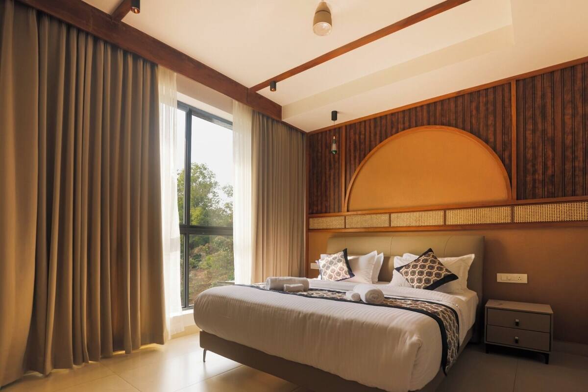 Un dormitorio moderno con una cama grande, una mesita de noche y una ventana con cortinas.