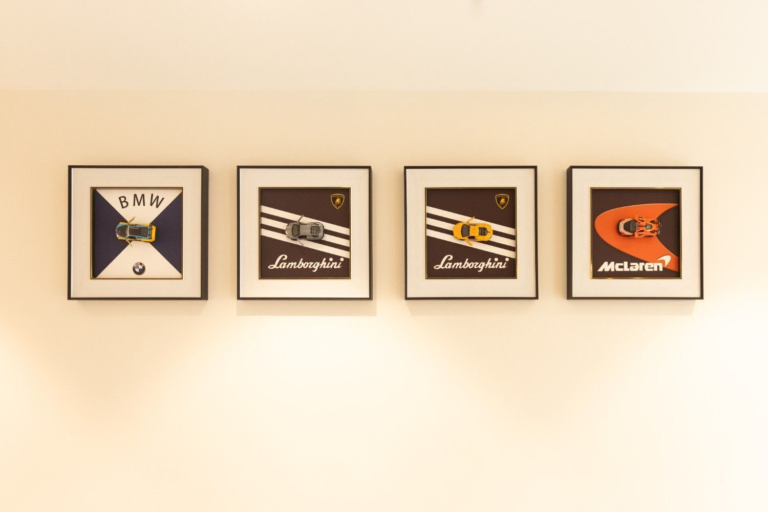 Four framed automotive logos on a wall.