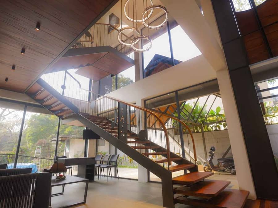 A modern interior with a staircase, seating area, and large windows.