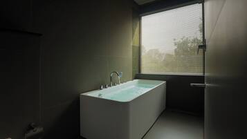 Un baño moderno con una bañera independiente, una ventana con persianas y una puerta.