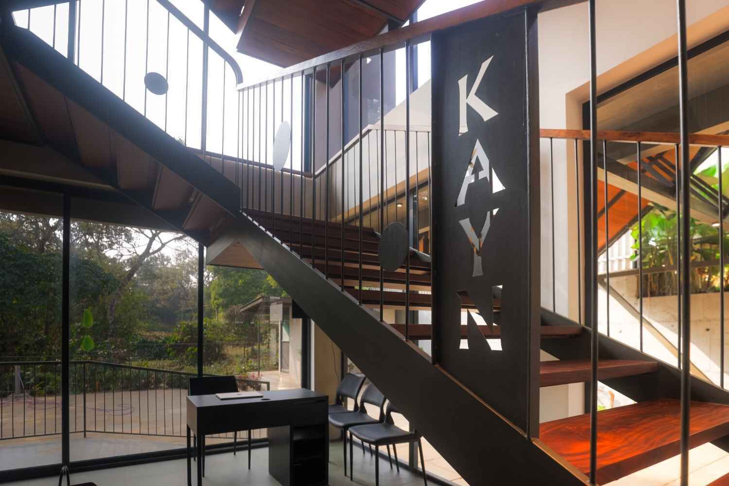 A modern interior with a staircase, a desk, and chairs.