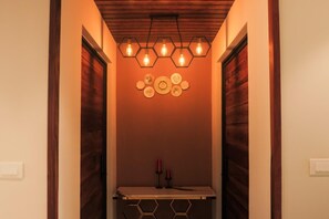 A hallway with a wooden ceiling, hexagonal light fixtures, and a wall-mounted plate decoration. - Kayn by spynora (Vythiri)