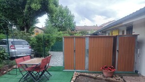 Un espacio exterior cercado con una mesa, sillas, un coche y un cobertizo de madera.