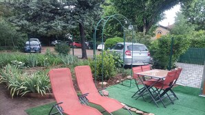 Un jardín con dos sillones rojos, una mesa y sillas.