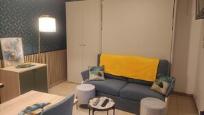 Una sala de estar con un sofá, una mesita, una lámpara y un aparador.