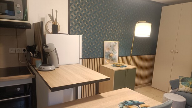 Una cocina compacta equipada con microondas, cafetera y comedor con mesa y sillas.