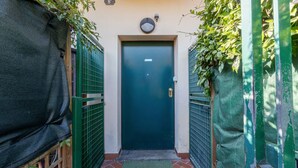 A narrow hallway with a green door, a small mat, and a security camera above the door. - Cozy 39m2 studio, ideal for an adult and a child up to 10 years old, located on the ground floor in lively Bolognina district. The location is strategic: the Fair, Tecnopolo & ring road are easily reachable, as are Central Station, the new Municipality h (Bologna)