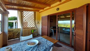Un porche cubierto con una mesa, sillas y vistas al campo.