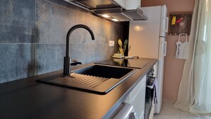 Una cocina moderna con un lavamanos negro, grifo de acero inoxidable y horno empotrado.