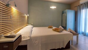 Una habitación de hotel con cama, mesita de noche, lámpara, armario y vistas al exterior.