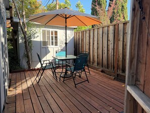 A wooden deck with a table and chairs, a patio umbrella, and a wooden fence. - Private fenced guesthouse perfect for a couple, near Stanford, Google, Facebook (Palo Alto)