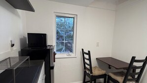 Una cocina compacta con microondas, una ventana pequeña y un comedor con dos sillas y una mesa.