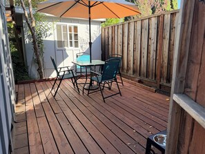 A wooden deck with a table and chairs, a patio umbrella, and a wooden fence. - Private fenced guesthouse perfect for a couple, near Stanford, Google, Facebook (Palo Alto)