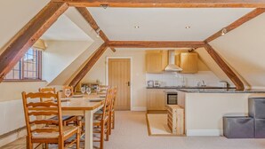 Una cucina in stile loft con travi in legno, un'area pranzo con tavolo e sedie, e vista all'esterno.