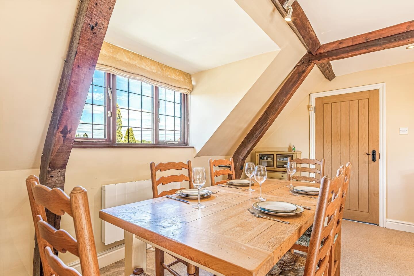 Un'area pranzo con un tavolo e sedie in legno, una finestra con vista e una porta sullo sfondo.