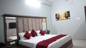 A bedroom with a bed, a mirror, a painting, and a small plant.