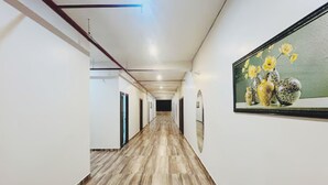 A long, narrow hallway with wooden flooring and white walls.