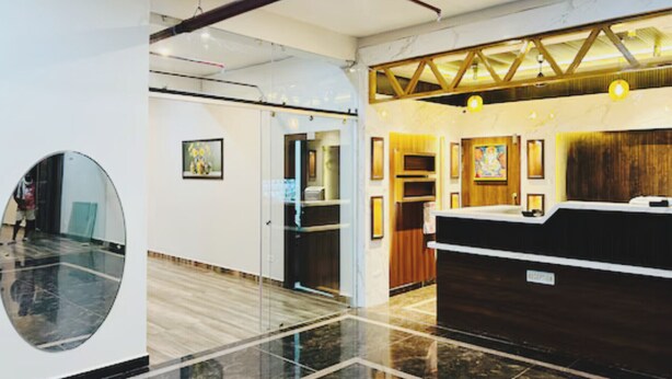 A reception desk with a wooden finish, a large mirror, and a tiled floor.
