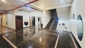 A spacious lobby with a polished marble floor, a staircase, and a large mirror.