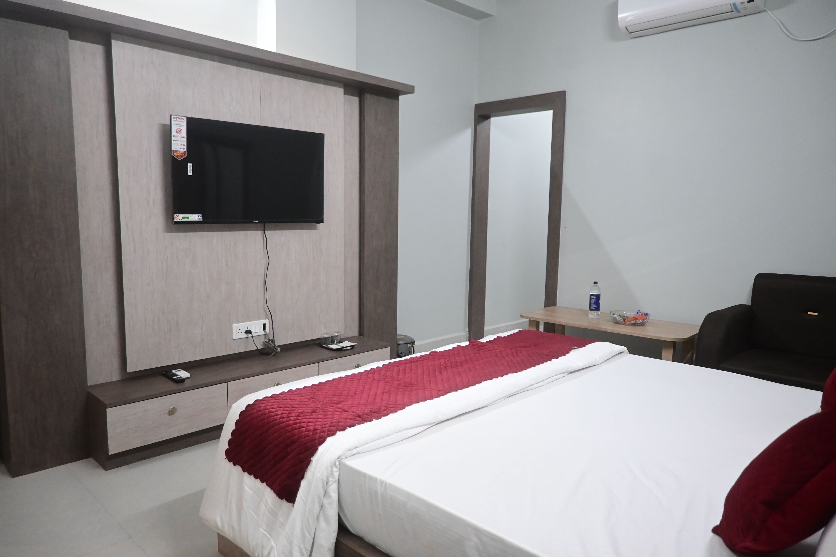 Hotelkamer met een bed, een aan de muur bevestigde televisie, een bureau met stoel en een spiegel.