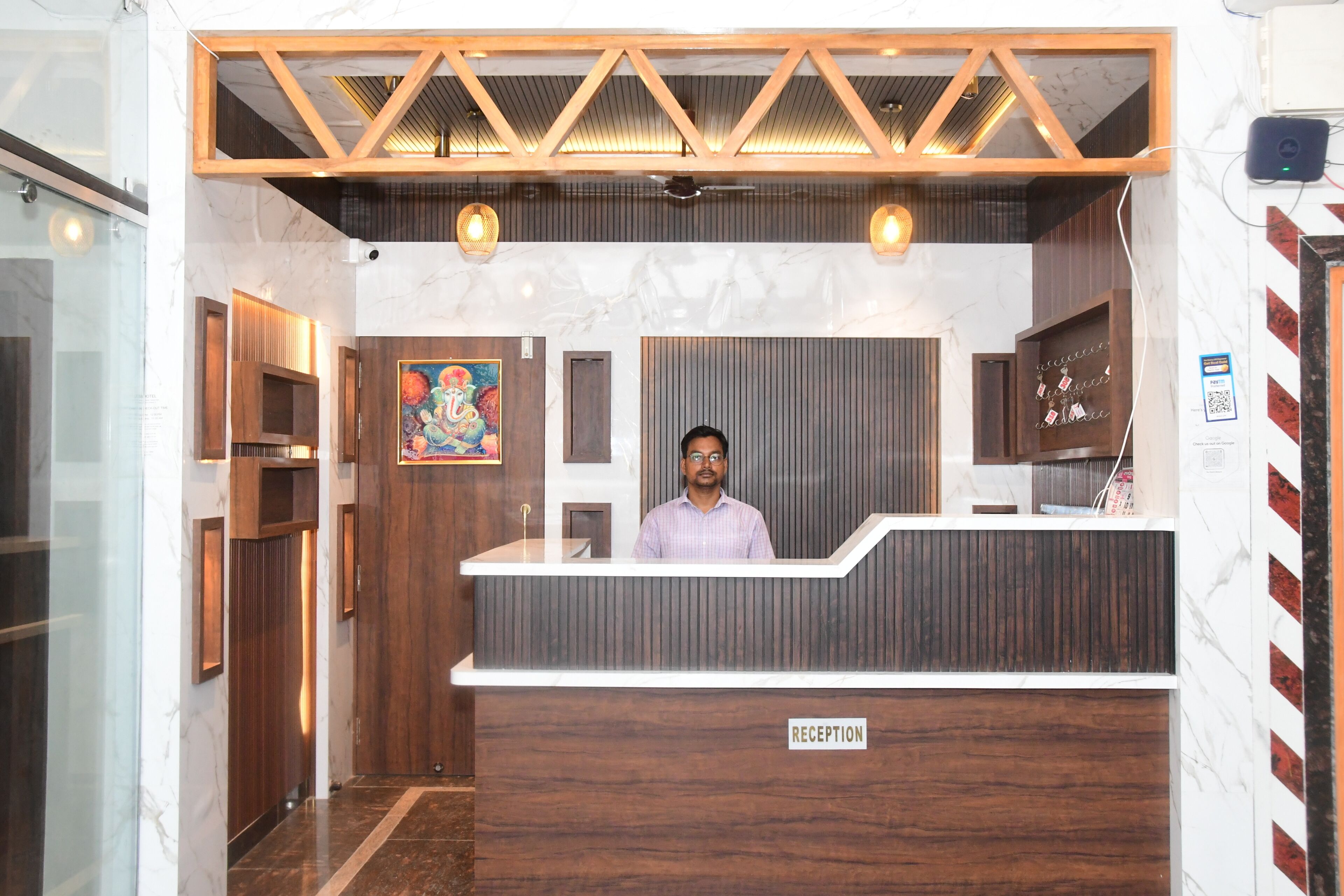 A reception area with a wooden reception desk, a marble wall, and a ceiling with wooden beams.