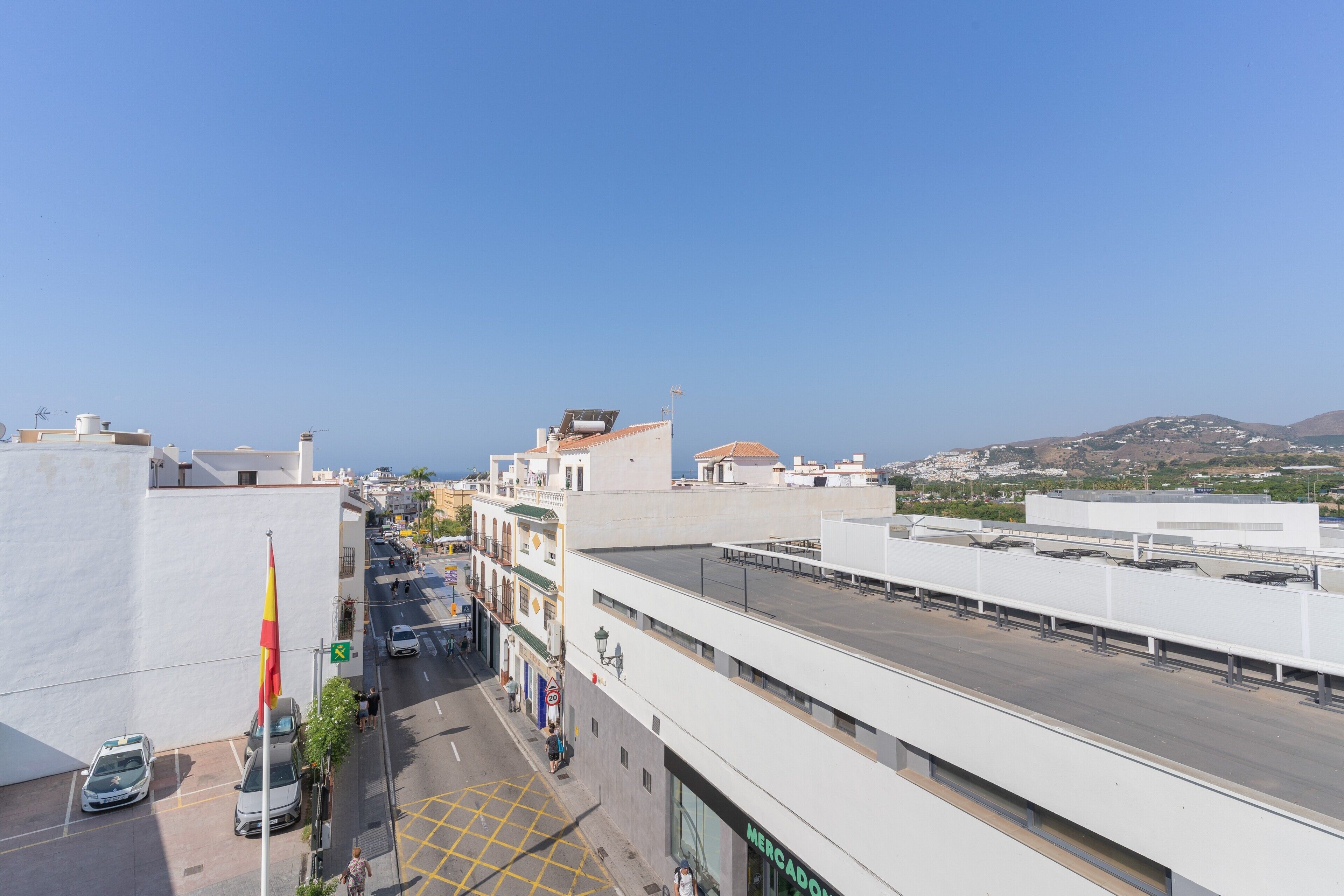 A street view with buildings, a flag, and a clear sky.