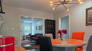 A dining area with a round table, orange placemats, black chairs, and a vase with red flowers. - World Cup Ready - Near Downtown & Museum District (Houston)