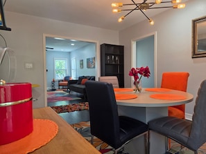 A dining area with a round table, orange placemats, black chairs, and a vase with red flowers. - World Cup Ready - Near Downtown & Museum District (Houston)