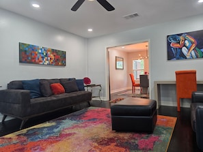 A living room with a sofa, ottoman, colorful rug, and artwork on the walls. - World Cup Ready - Near Downtown & Museum District (Houston)
