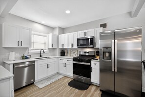 A modern kitchen with white cabinets, stainless steel appliances, a microwave, oven, and refrigerator. - World Cup Ready - Near Downtown & Museum District (Houston)