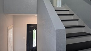 A staircase with a handrail, a door with a glass window, and a wall with a textured finish. - World Cup Ready - Near Downtown & Museum District (Houston)