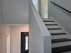A staircase with a handrail, a door with a glass window, and a wall with a textured finish. - World Cup Ready - Near Downtown & Museum District (Houston)