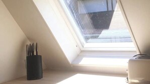 Une fenêtre de toit, un porte-ustensiles noir et un appareil électroménager blanc, le tout posé sur une surface en bois.
