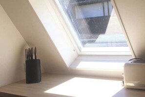 Ein Dachfenster, ein schwarzer Utensilienhalter und ein weißes Gerät auf einer Holzbeschichtung.