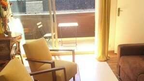 Une pièce comprenant un canapé, un fauteuil, une petite table et une fenêtre donnant sur une clôture en bois.