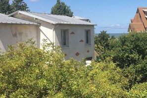 Ein Gebäude mit schrägem Dach, zwei Fenstern und einer teilweise sichtbaren Tür.