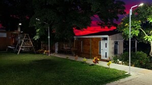 A small building with a wooden exterior, a bench, and a tree in the foreground.