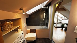 Ein kleines Badezimmer mit Waschmaschine, Badewanne und Dusche.