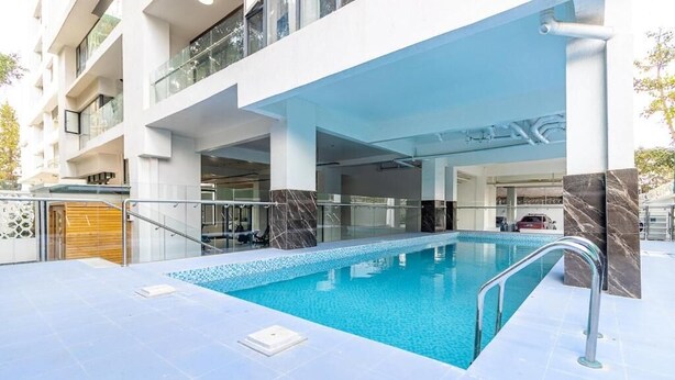 Een modern hotel met een zwembad, glazen balustrades en een meerlaags gebouw.