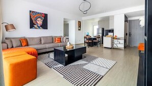 Een moderne woonkamer met een bank, een poef, een salontafel en kunst aan de muur.