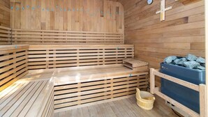 Een houten sauna met banken, een thermometer en een emmer.
