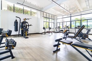 A gym with various exercise equipment, large windows, and a high ceiling. - Jireh Dwellings Spacious 2Br Comfort with fitness and spacious rooms (Nairobi)