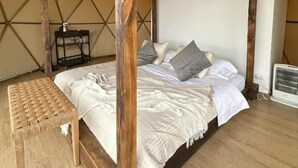 Habitación tipo tienda de campaña con cama, banco y calentador.