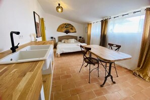 Une chambre à coucher avec un lit, des tables de chevet, une table en bois et une chaise.
