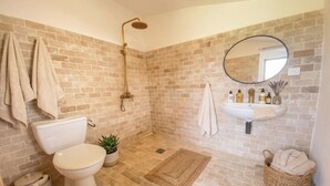 Et badeværelse med bruser, toilet, vask og en potteplante.